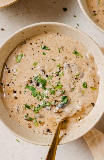 Two bowls of chicken corn soup garnished with parsley.
