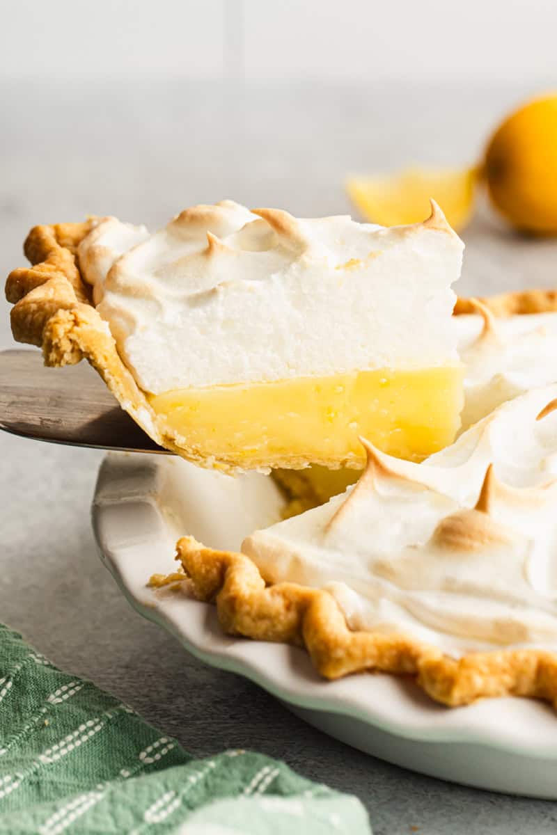 A slice of an easy lemon pie recipe being lifted out of the pie plate with a spatula, showing the lemon and meringue layers.
