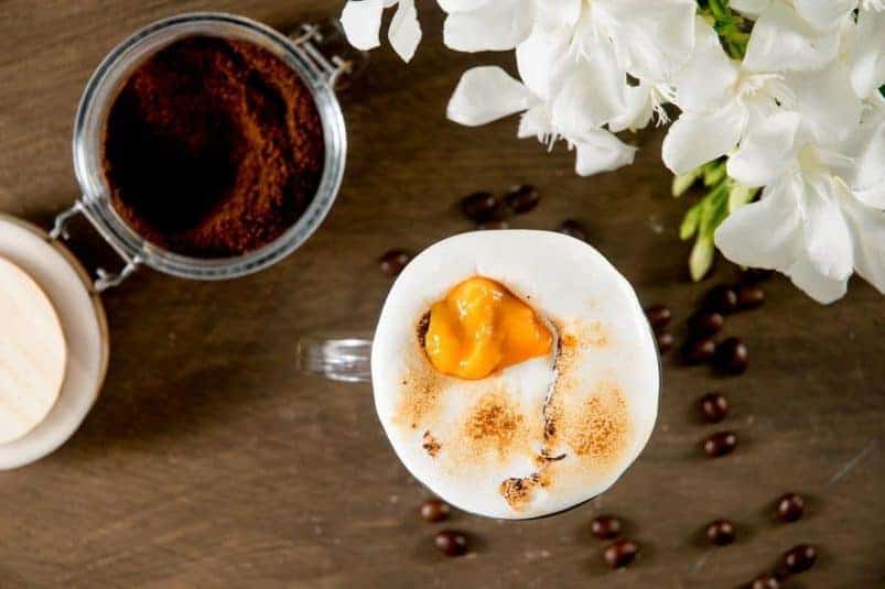 Marshmallow pumpkin latte in a mug, coffee grind on the side.