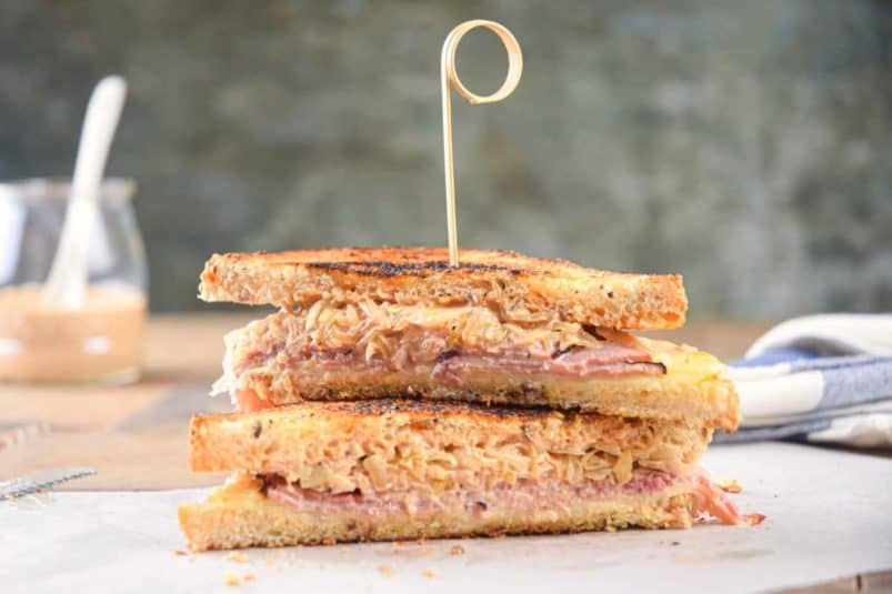 Reuben sandwiches stacked with a toothpick.
