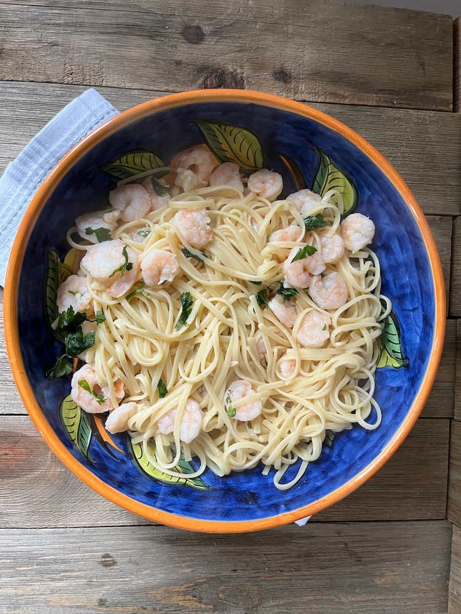 A fork holding a piece of cooked salmon, with more salmon fillets, lemon slices, and seasoning shakers in the background.