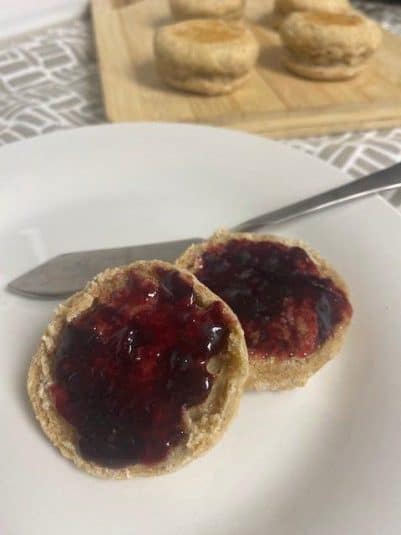 Close up of lemon bars on white plate with sliced lemons in background.