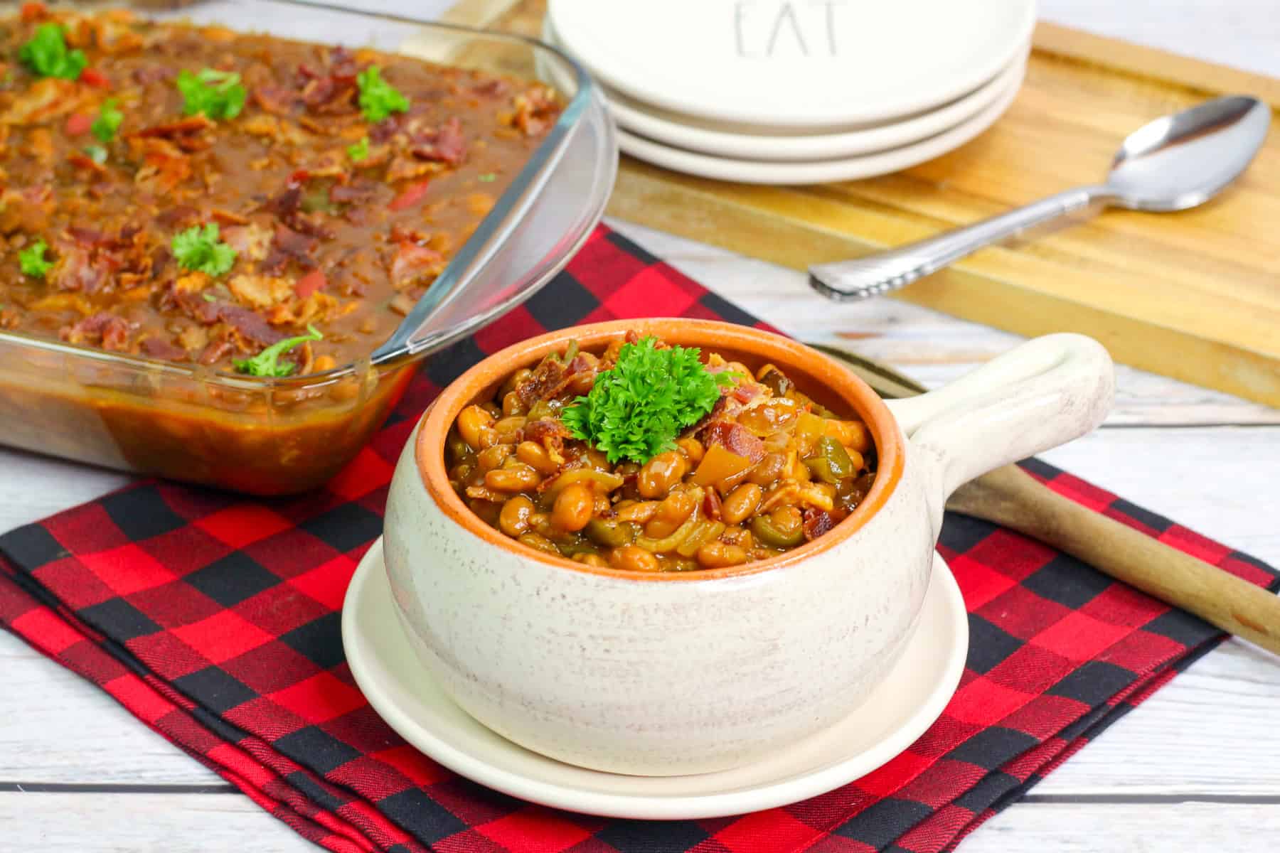 a bowl of bbq baked beans with a 9x13 pan of beans in the background. 