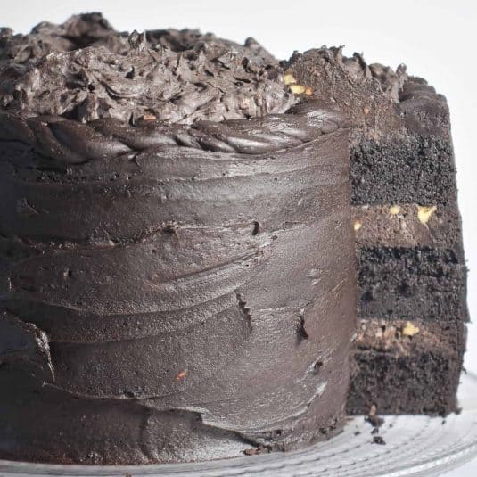 Black Velvet layer cake, with a slice cut and partly pulled out showing the layers. The cake is on a glass cake stand.