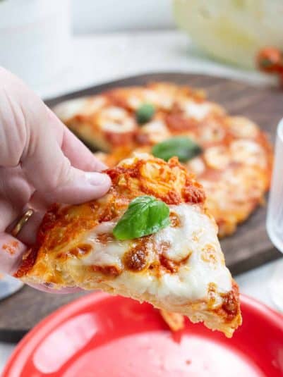 Cabbage Pizza Margarita held by a hand.