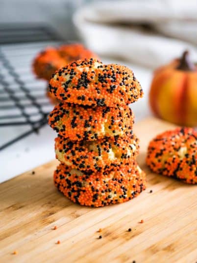 Two sugar cookie bars with sprinkles on a wooden cutting board.