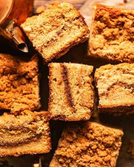 Cardamom coffee cake cut into squares and scattered about on a piece of parchment paper.
