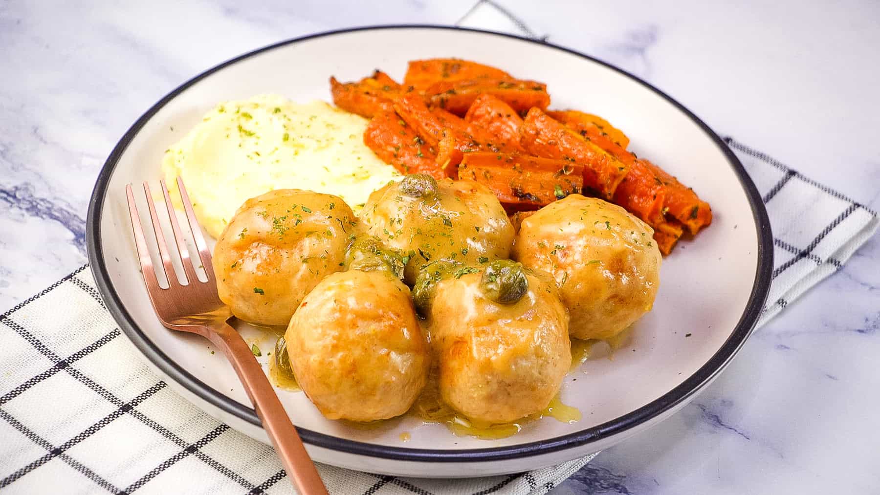 chicken meatballs in a lemon butter caper sauce served with mashed potatoes and carrots.