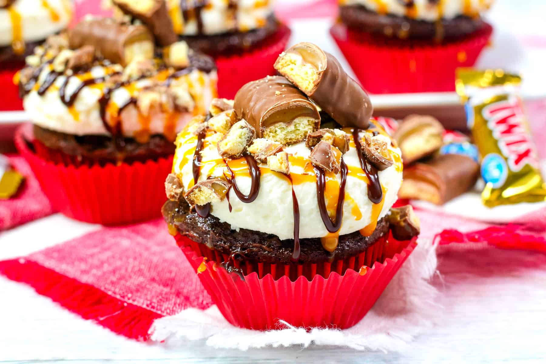 a twix cupcake topped with caramel frosting and caramel and chocolate sauces.
