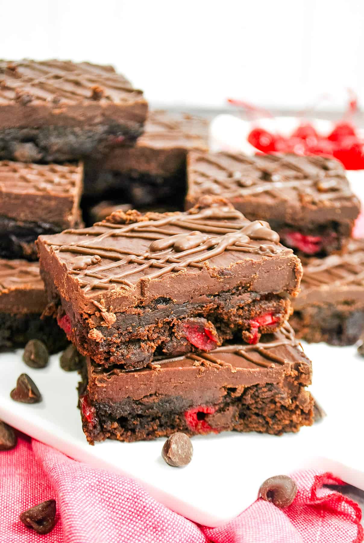 two chocolate cherry brownies stacked on top of each other and topped with chocolate ganache.