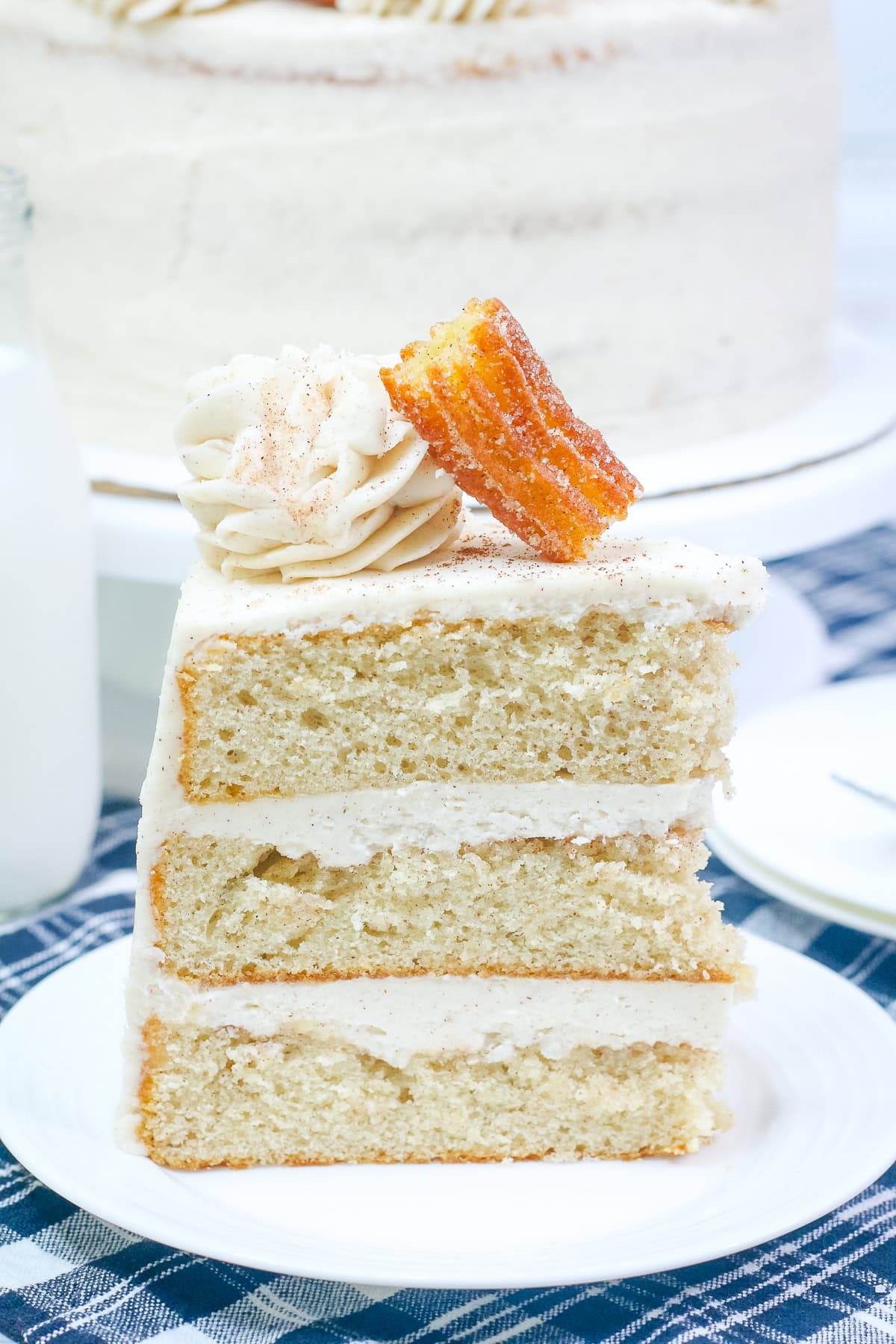 a vanilla cake with cinnamon sugar and cinnamon buttercream topped with a churro.