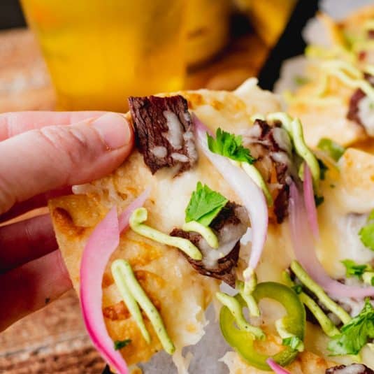 Hand pulling chip off of elk steak nacho pan.