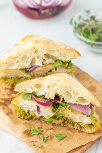 A pesto chicken sandwich cut in half.
