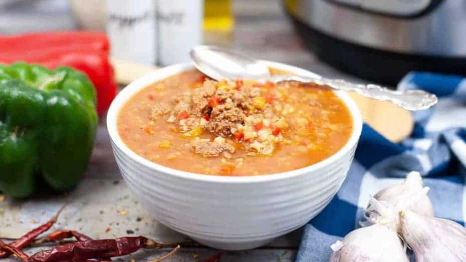 Low angle shot of a white bowl filled with tortilla soup. There is an instant pot in the background.