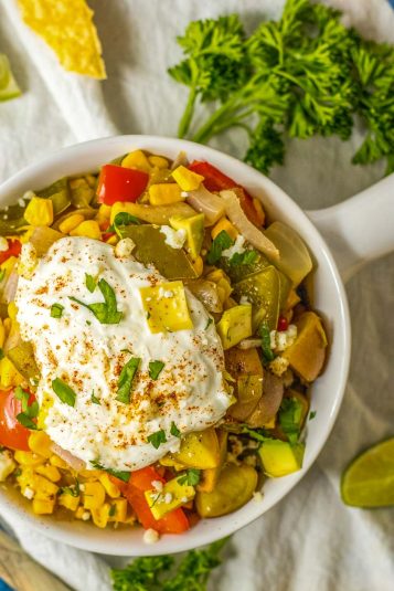Cheese covered slow cooker chili mac in the crock pot with a wooden spoon.