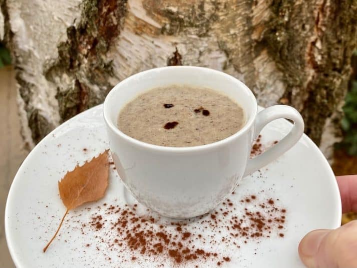 Cup and saucer of mushroom soup dusted with cocoa powder.