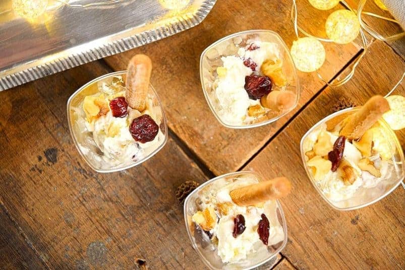 Goat cheese shots with mini breadsticks and Christmas lights on wooden background.