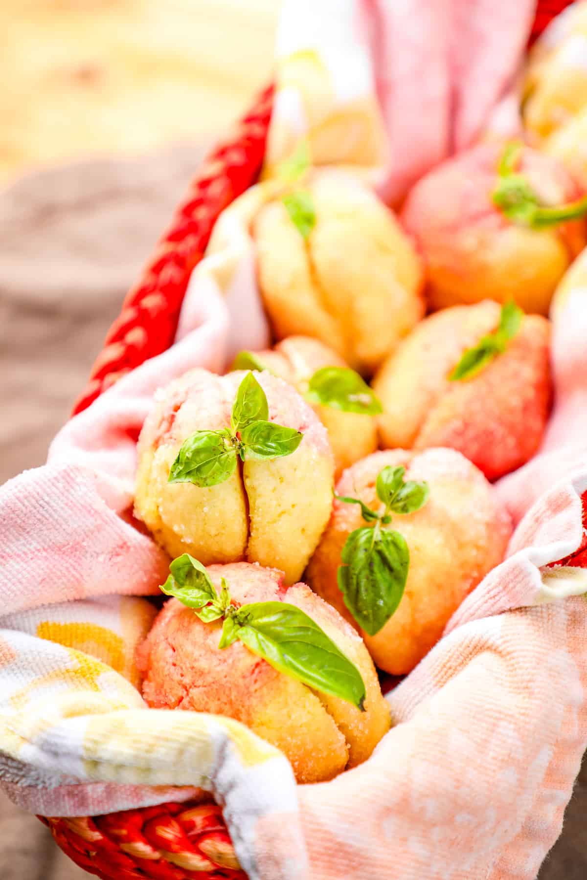 Sweet fruit muffins garnished with fresh basil in a woven basket.