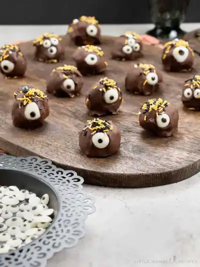 Monster Pumpkin Cheesecake Truffles on a wooden board.