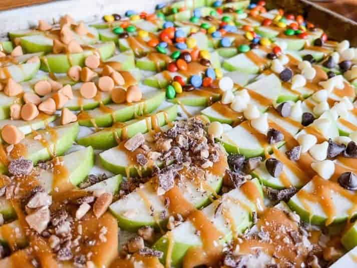 Pan of sliced apples with caramel apple toppings.