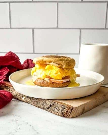 A turkey smash burger on a wooden cutting board in front of subway tile.