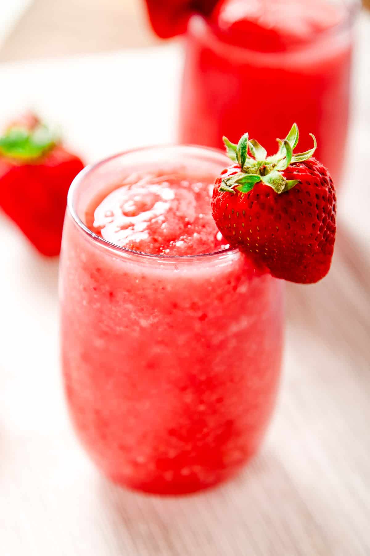 a strawberry white wine slushie in a glass garnished with a strawberry.