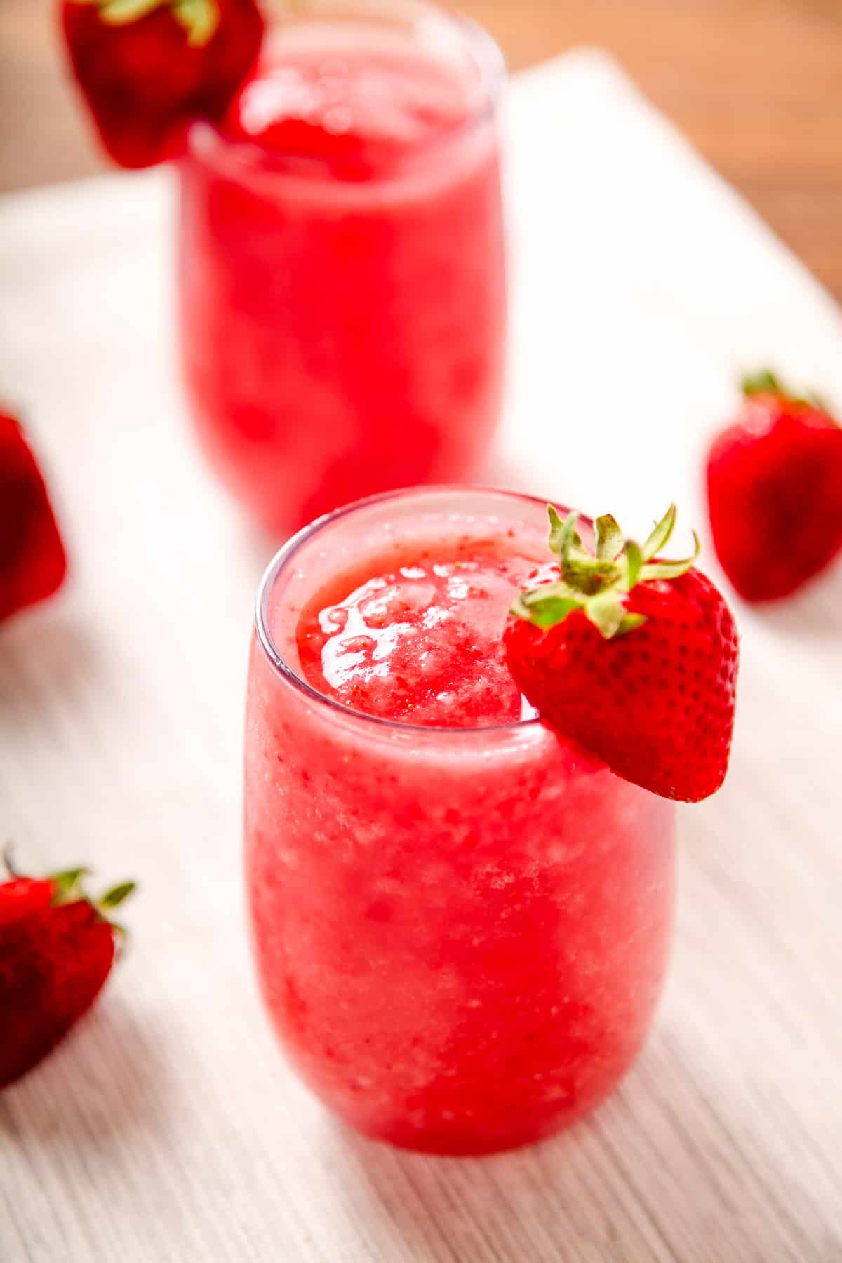  a strawberry white wine slushie in a glass garnished with a strawberry.