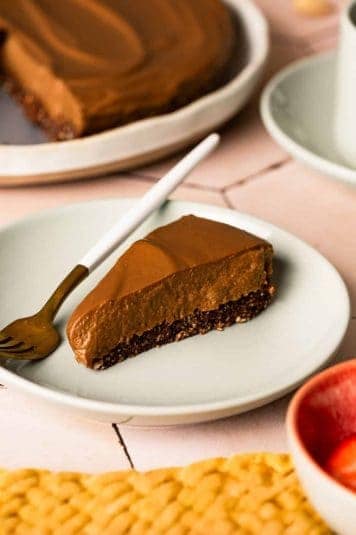 A slice of chocolate torte on a plate with a fork on the plate.