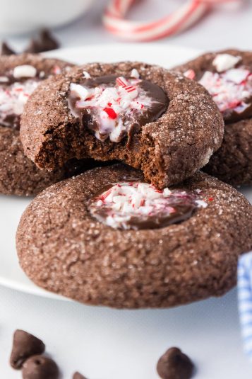 Chocolate peppermint cookies on a plate with a bite missing from the top cookie.