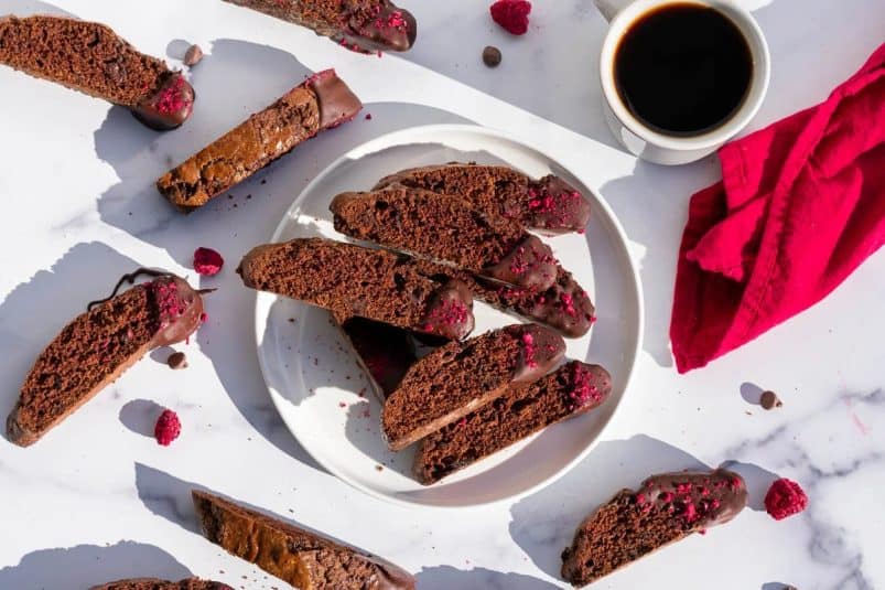 Chocolate Raspberry Sourdough Biscotti on a plate with a cup of coffee.