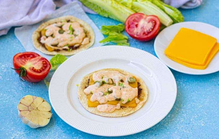 Flat taco on a white plate on a blue background.
