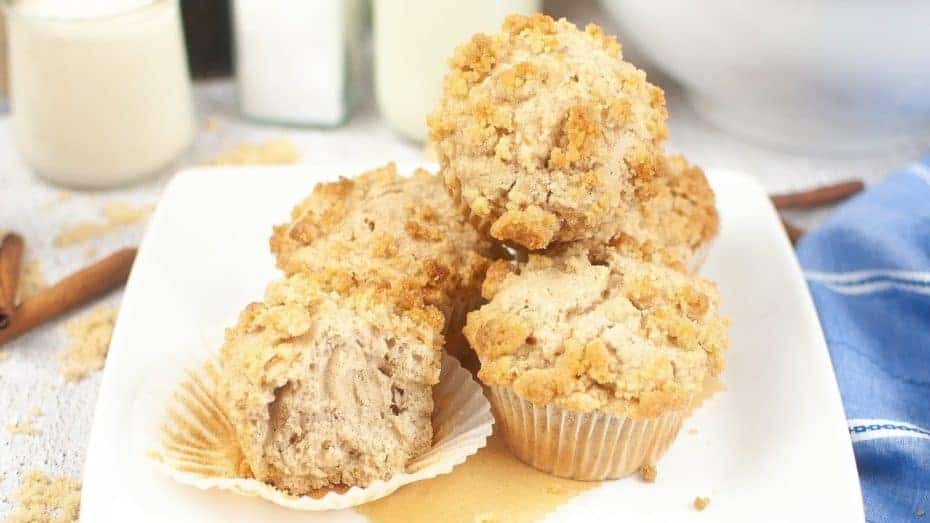 A glass jar filled with fish-shaped cheese crackers on a wooden table, surrounded by scattered crackers and cheese shreds.