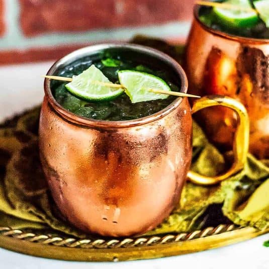 Two virgin moscow mules garnished with lime on a gold platter.