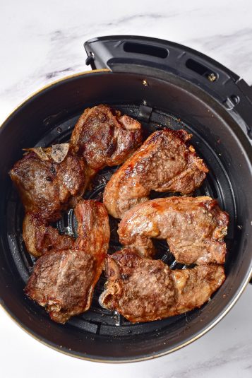 Air fryer lamb chops in air fryer basket.