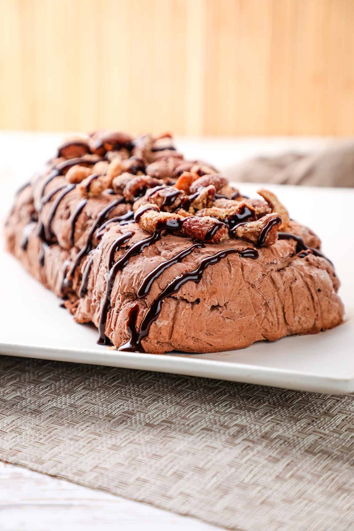 an unmolded chocolate semifreddo drizzled with chocolate sauce and topped with nuts.