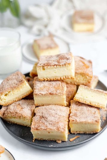 churro cheesecake bars stacked on a plate.