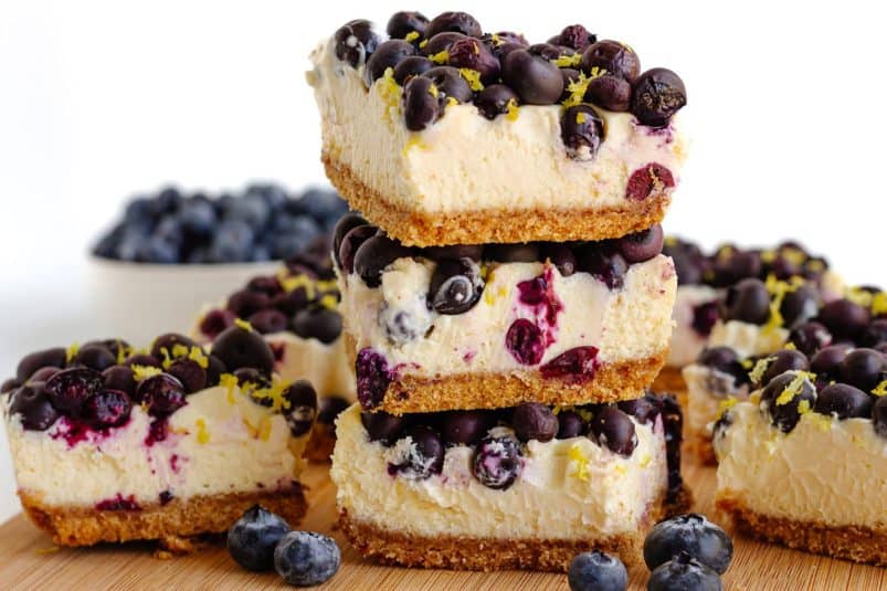 Lemon blueberry cheesecake bars on a wooden board.
