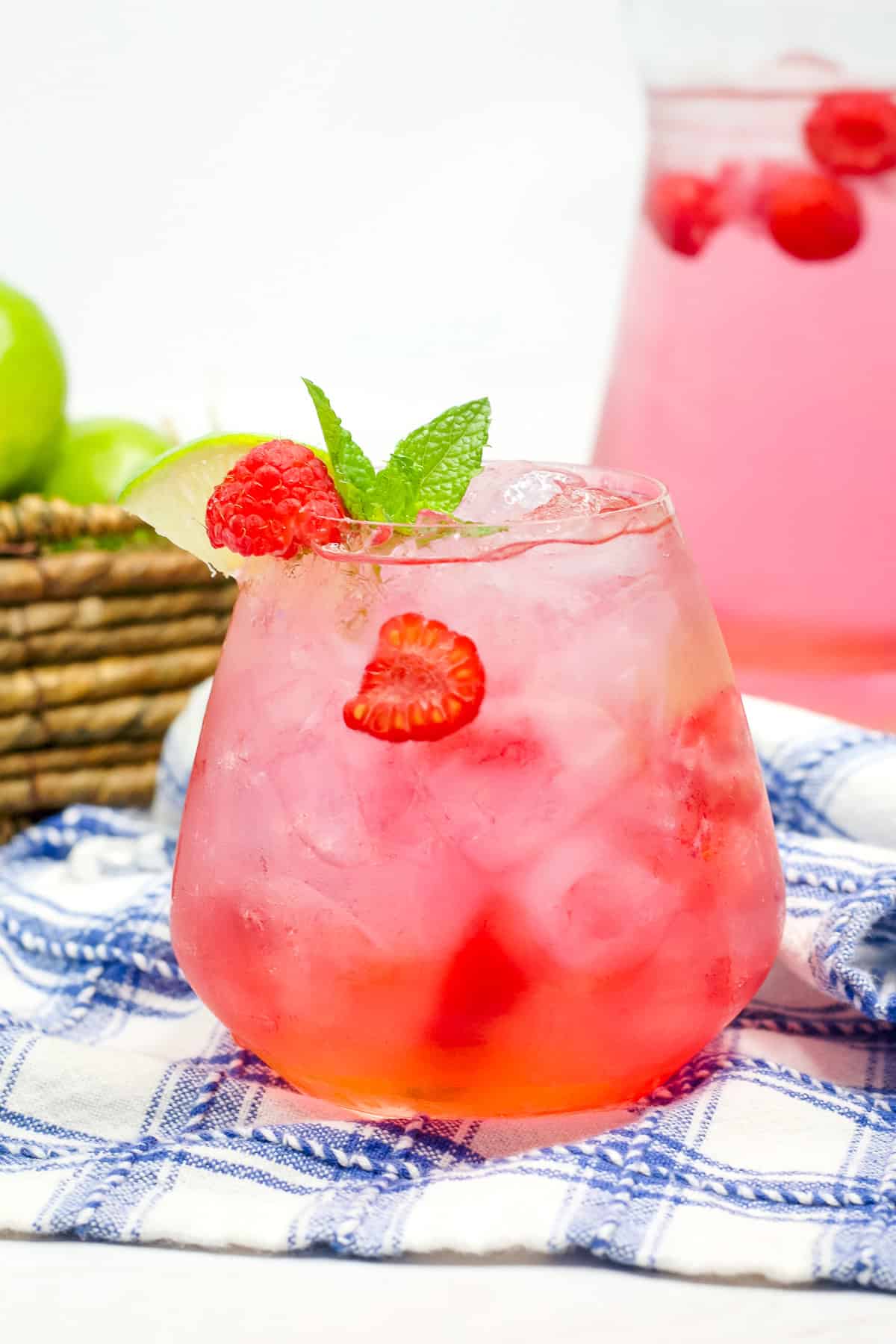 A raspberry lime ,rickey cocktail garnished with raspberries, lime, and fresh mint.