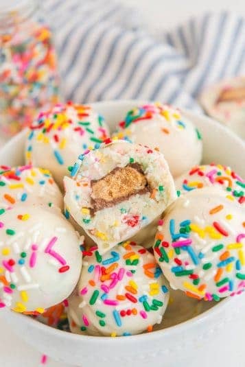 Colorful cake balls with rainbow sprinkles in a white bowl, perfect for celebration desserts.