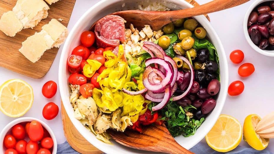 Colorful Mediterranean pasta salad with olives, cherry tomatoes, and fresh herbs on a white plate.