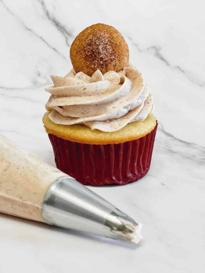 Delicious vanilla cupcake with cinnamon-spiced frosting and a cookie on top, perfect for baking and dessert recipes.