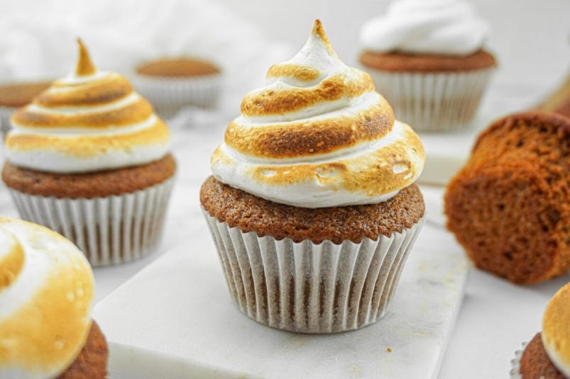 Homemade marshmallow frosting that's been toasted and piped onto a gingerbread cupcake. More cupcakes in the background.