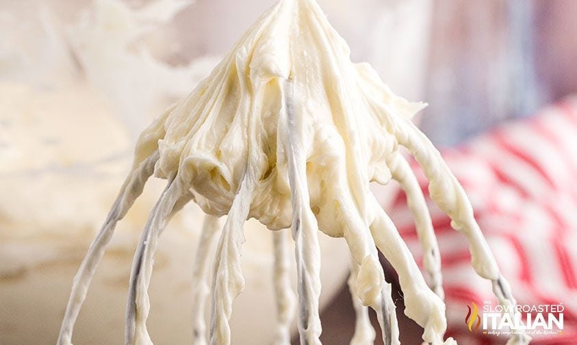 Fluffy whipped cream frosting on spoon, close-up of creamy dessert topping.