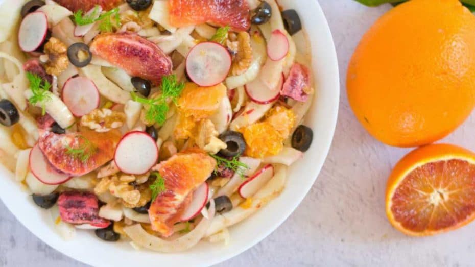 Fresh fruit salad with figs, radishes, mixed nuts, and herbs, served with oranges. Perfect healthy dessert or snack option.