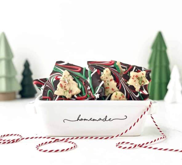 Sugar Cookie Dough Bark in a ceramic tray with Christmas trees in the background.