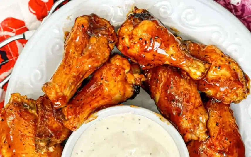 Three air-fried, sesame-crusted chicken thighs with broccoli on a white plate.