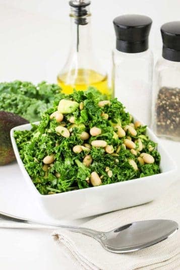 Fresh kale salad with pine nuts and avocado, ideal for healthy eating and meal prep.