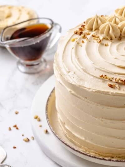 Creamy vanilla frosted cake with chopped nuts on top, perfect for special occasions.