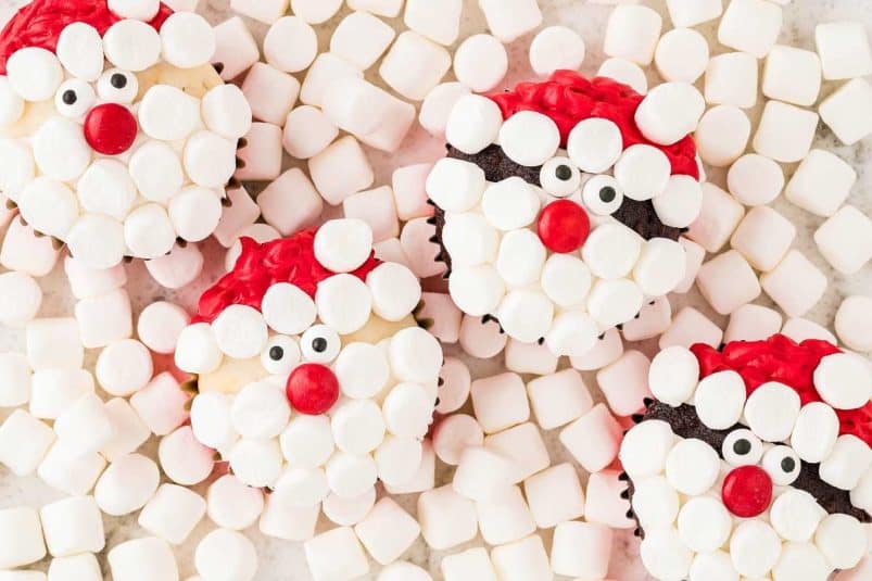 Santa cupcakes with marshmallows and Christmas-themed decorations.