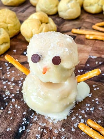 A Snowman Cream Puff on a cutting board.